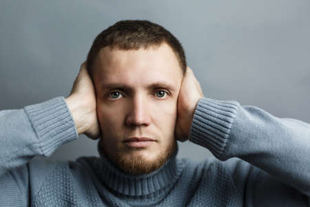 Man covered his ears with his hands. Concept of hearing nothing be in silence. On a gray background. Studio photo.の写真素材