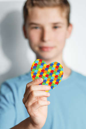 child holds jigsaw pattern heart in his hands. mental health care concept. World Autism Awareness dayの写真素材
