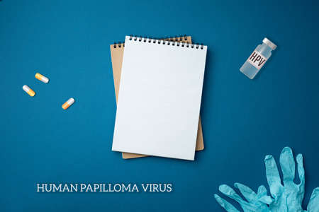 Spiral notebook with surgical gloves and face mask on blue background close up flat lay. Pandemic protection concept against coronavirus top view.の写真素材