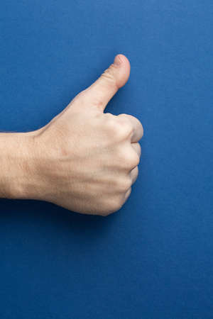 Hand showing thumb up on a blue isolated background. Recommends something. Copy space aside for your advertising content.の写真素材