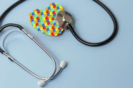 Stethoscope on blue background with jigsaw pattern heart, free space, concept medicine and doctors office. World Autism Awareness dayの写真素材