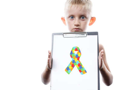 little boy holding tablet with puzzle ribbon. World Autism Awareness day. symbol combating cancer...