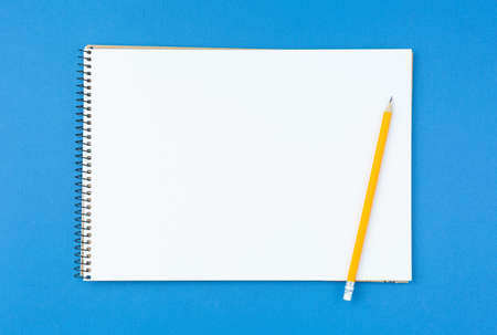 Spiral notebook and pencil on blue isolated background. Design concept with copy space for notes....