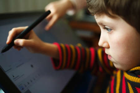 Little girl draws on a graphics tablet. Creative education concept. Close up view.
