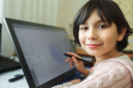 Little girl draws on a graphic tablet. Creative education concept. Close up view.の写真素材