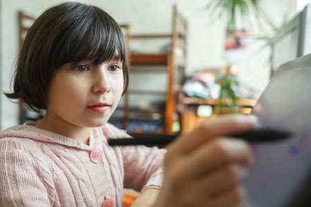 Little girl draws on a graphic tablet. Creative education concept. Close up view.
