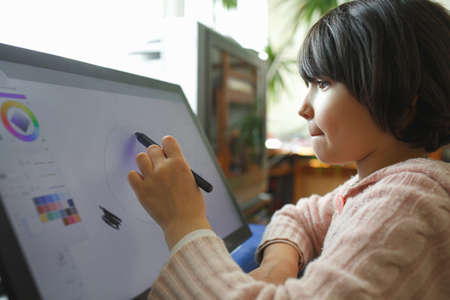 Little girl draws on a graphic tablet. Creative education concept. Close up view.の写真素材