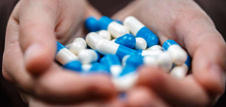 Child hands holds handful of pills on white isolated background. Backlight Photo. Healthcare and medical concept. Prevention of bacterial infection coronavirus or Covid 19.の写真素材