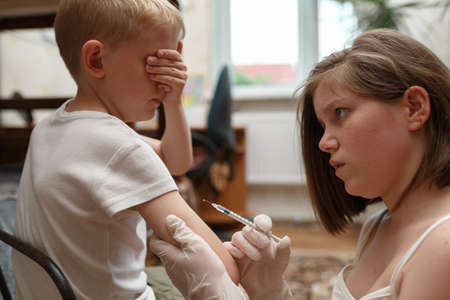 Boy closed his eyes and does not look at medical syringe with vaccine. Health care and medicine...