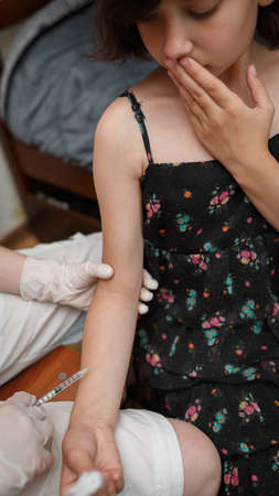 Little girl worried before injecting vaccination in arm. Medical syringe with vaccine. Health care...