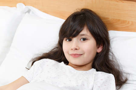 cute little girl on the bed woke up in the morning in her bed. soft white bed for a child, good mood...