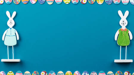 Easter background with painted eggs and rabbits on blue background top view, festive background with...