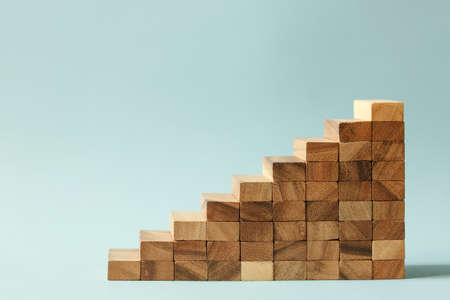 Stairs of natural color wooden blocks on blue background. Concept of growth and success plan.