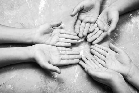 children's hands together in a circle with their hands up on a gray background, top view. joint...