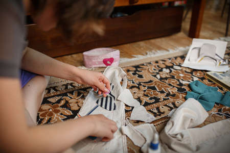 Girl is engaged in needlework at home. Carves hearts out of fabric. Free time hobby.