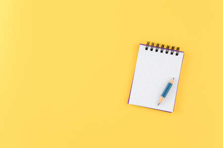 open empty notepad with pencil on isolated yellow background flat lay. top view. school concept, a...