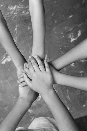 children's hands together in a circle with palms down on a gray background, top view. joint support...