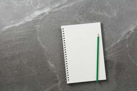 open notebook with green pencil on marble background top view, school notepad on a dark table, office desk flat layの写真素材
