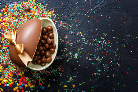 easter composition top view. chocolate eggs with colorful candies on black background flat lay with space for textの写真素材