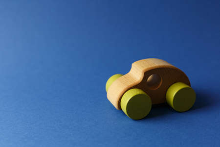 Wooden toy car with yellow wheels Concept of environmentally friendly toys for children on a blue background horizontal photo side view.の写真素材