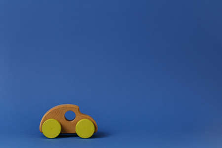Wooden toy car with yellow wheels Concept of environmentally friendly toys for children on a blue background horizontal photo side view.の写真素材
