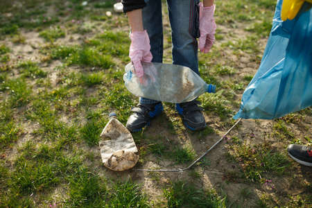 little boy in the park collect plastic bottles in a plastic bag, child scavenge on the...