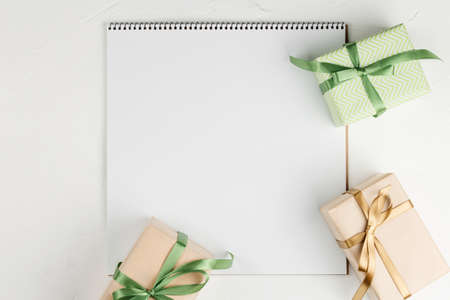 Gifts on blank notebook sheet on a white background, top view. Flat lay with copy space....