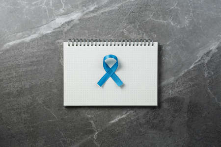 blue prostate ribbon on open notebook isolated on marble background, prostate cancer and symbol of helping HIV patientsの写真素材