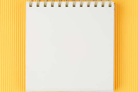 open notebook on corrugated yellow background top view, spiral notepad with blank sheet, flat lay....