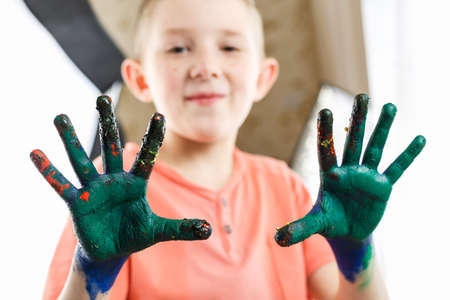 boy paint with hands on the table, drawing lesson at school. schoolchildrenâs hands are painted with paint, a social experiment with paintsの写真素材