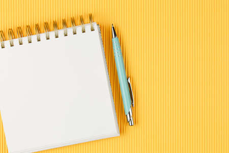 notebook on corrugated yellow background with pen top view, spiral notepad with blank sheet, flat lay. school concept, desktop of businessman.の写真素材