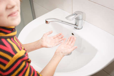 Smiling girl shows her palms with soap in the bathroom in front of the sink Morning hygiene.