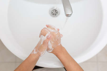 Morning hygiene washing hands with soap in the sink, bathroom procedures.の写真素材