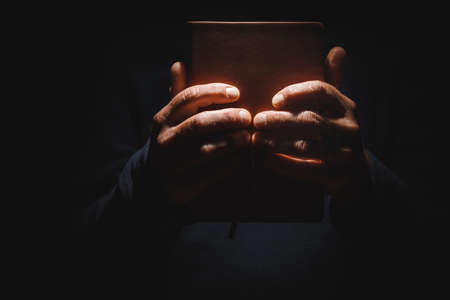 Male hands are holding a closed book on Black isolated background Concept of the Bible or personal...