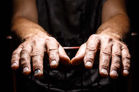 Male weary hands, palms down on a black isolated background. Concept of Hope and Support.の写真素材