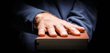Male hand laid on top of a hardcover book oath taking concert. Horizontal photo banner.の写真素材