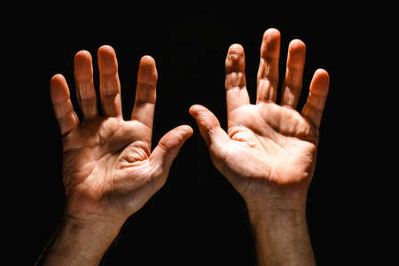 Hands reaching upwards with open palm on black isolated background. Concept of Hope and Support.の写真素材
