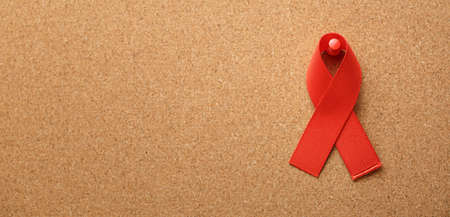 red AID ribbon on the cork table, symbol of the fight against AIDS, HIV and cancer. concept of...