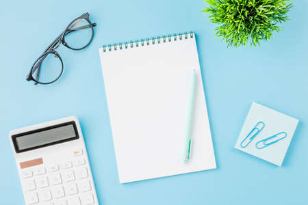 Office desk with calculator, notepad and glasses.の写真素材