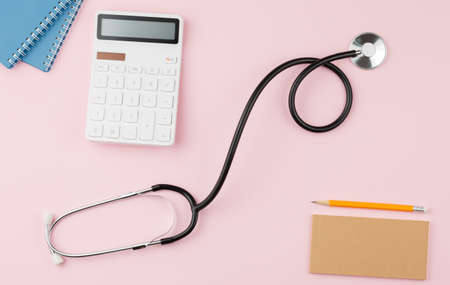 Calculator with a stethoscope on a pink table.の写真素材