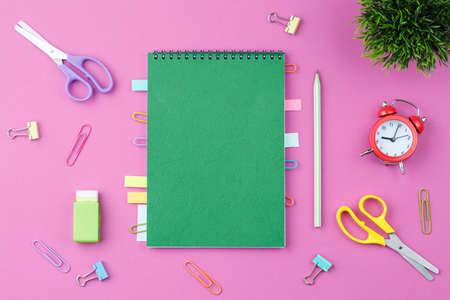 Green notepad with stationery on a pink backgroundの写真素材