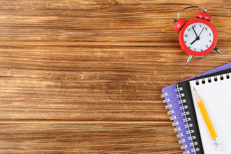 Notepad with school supplies on a wooden desk.の写真素材