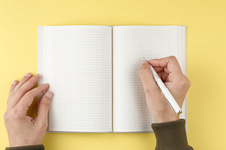 White pen in hand over an open notebook.の写真素材