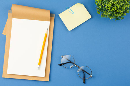 Notepad with pencil, glasses, plant and note sheetの写真素材