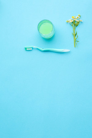 Mouthwash in a glass and a toothbrush.