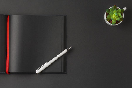 Black notebook white pen and Green plantの写真素材