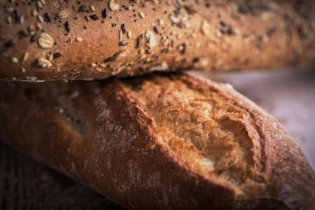 Macro view of fresh crunchy baguette bread with sunflower seeds and other seeds on the rustic wooden...