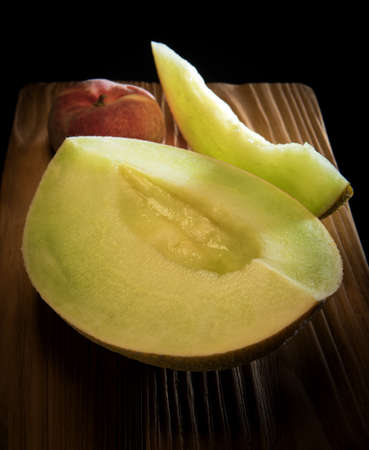 Juicy mellow melon and peach on the wooden rustic desk on the black backgroundの写真素材