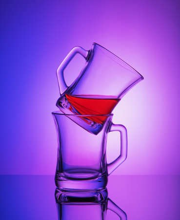 Close view of two empty crystal cups with the rest of tea on the gradient blue and purple...
