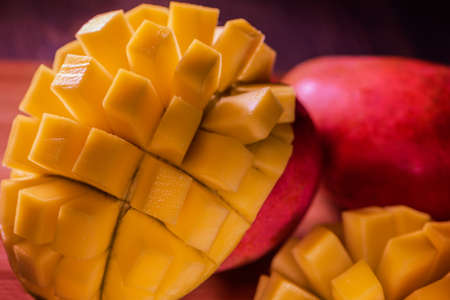 Natural Fresh Ripe Mango ubes, Slices close up, Macro shooting. On the dark blue or black background. On the rustic wooden board and bamboo napkinの写真素材